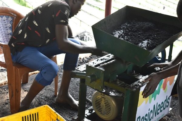 Youth learning how to use the briquette machine